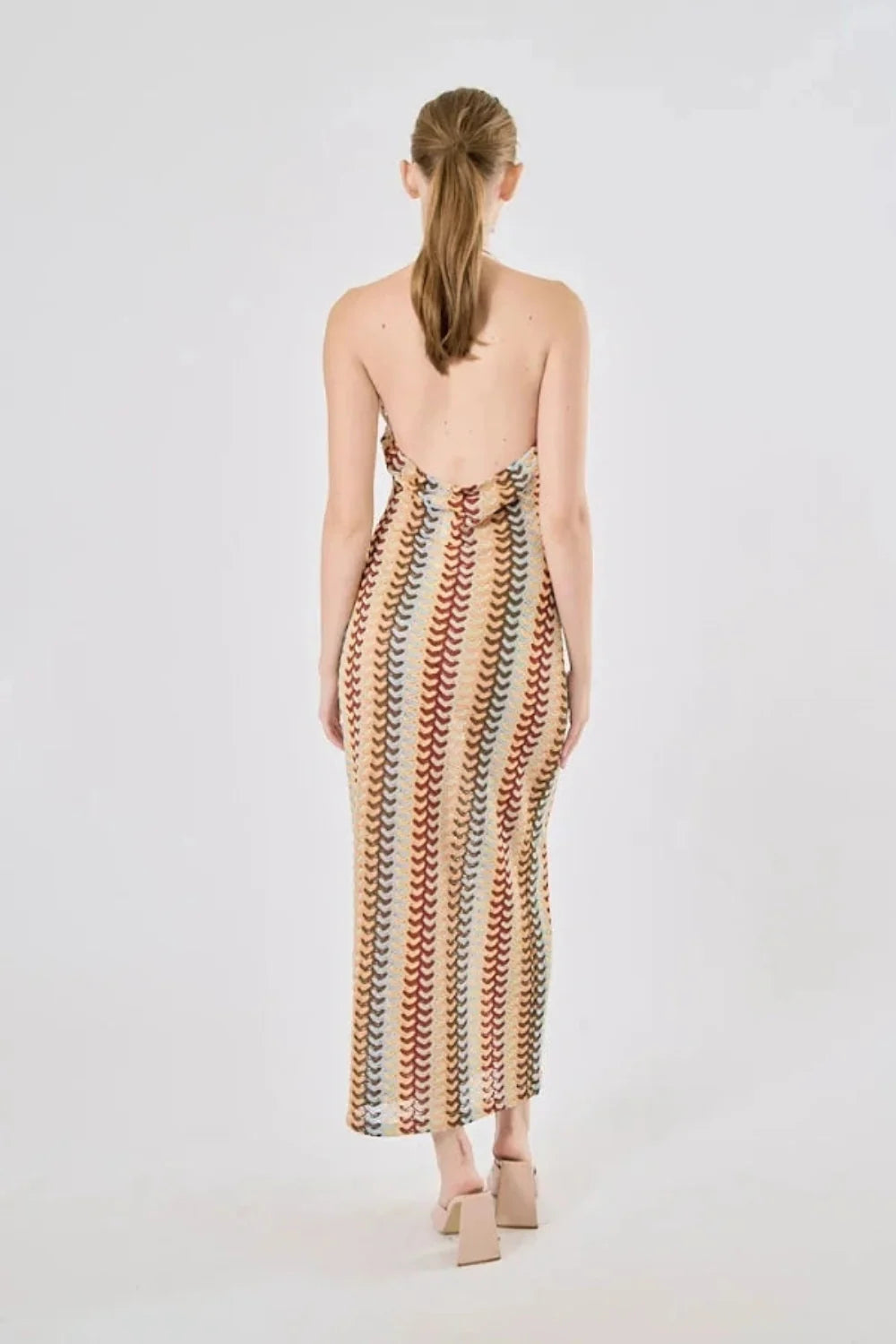 Model viewed from the back wearing the Kouvr Fashion 70s-inspired retro wave print halter maxi dress, showcasing the open-back design