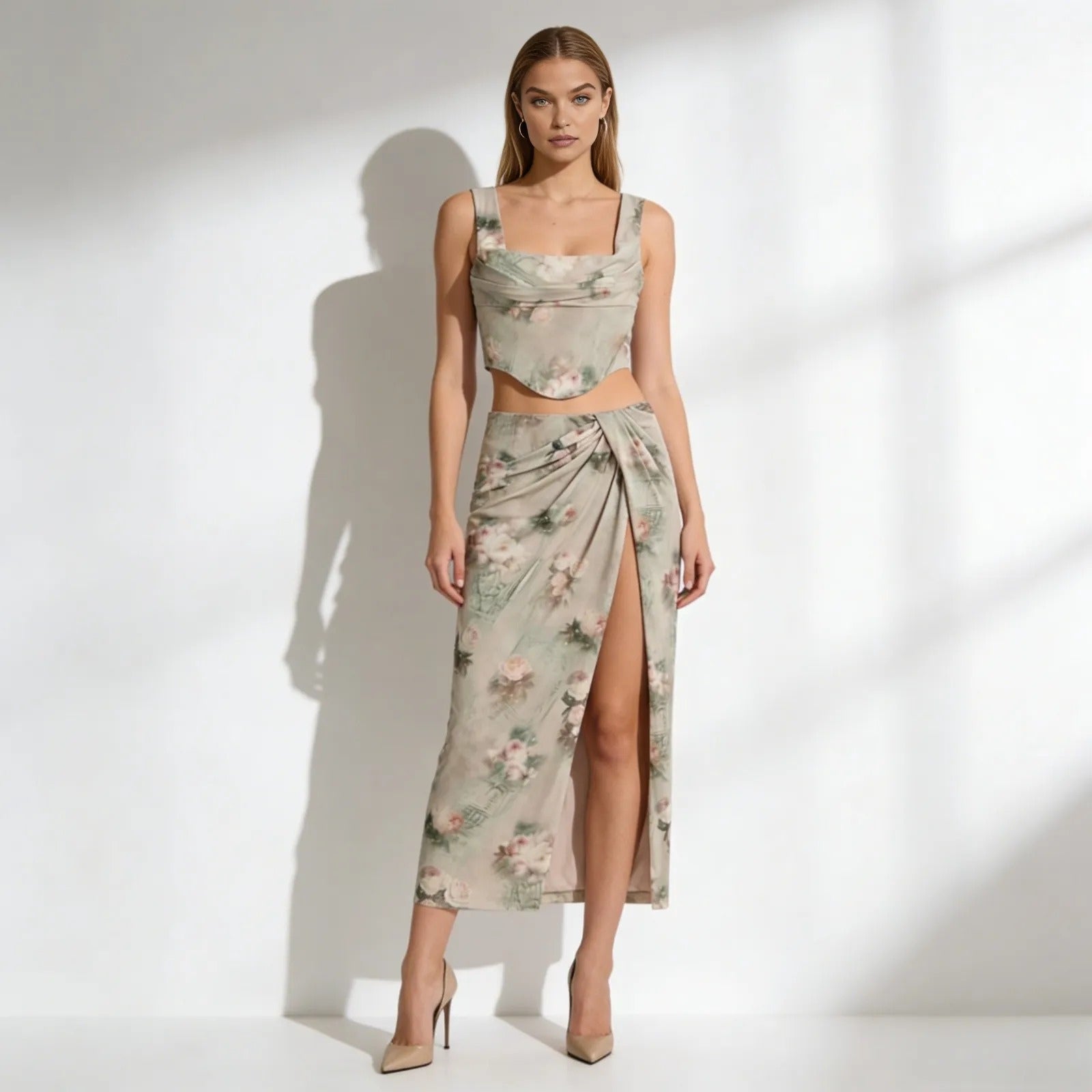 Model wearing the Kouvr Fashion Rona set in a sage green floral print, featuring a corset top and a high-slit draped maxi skirt.