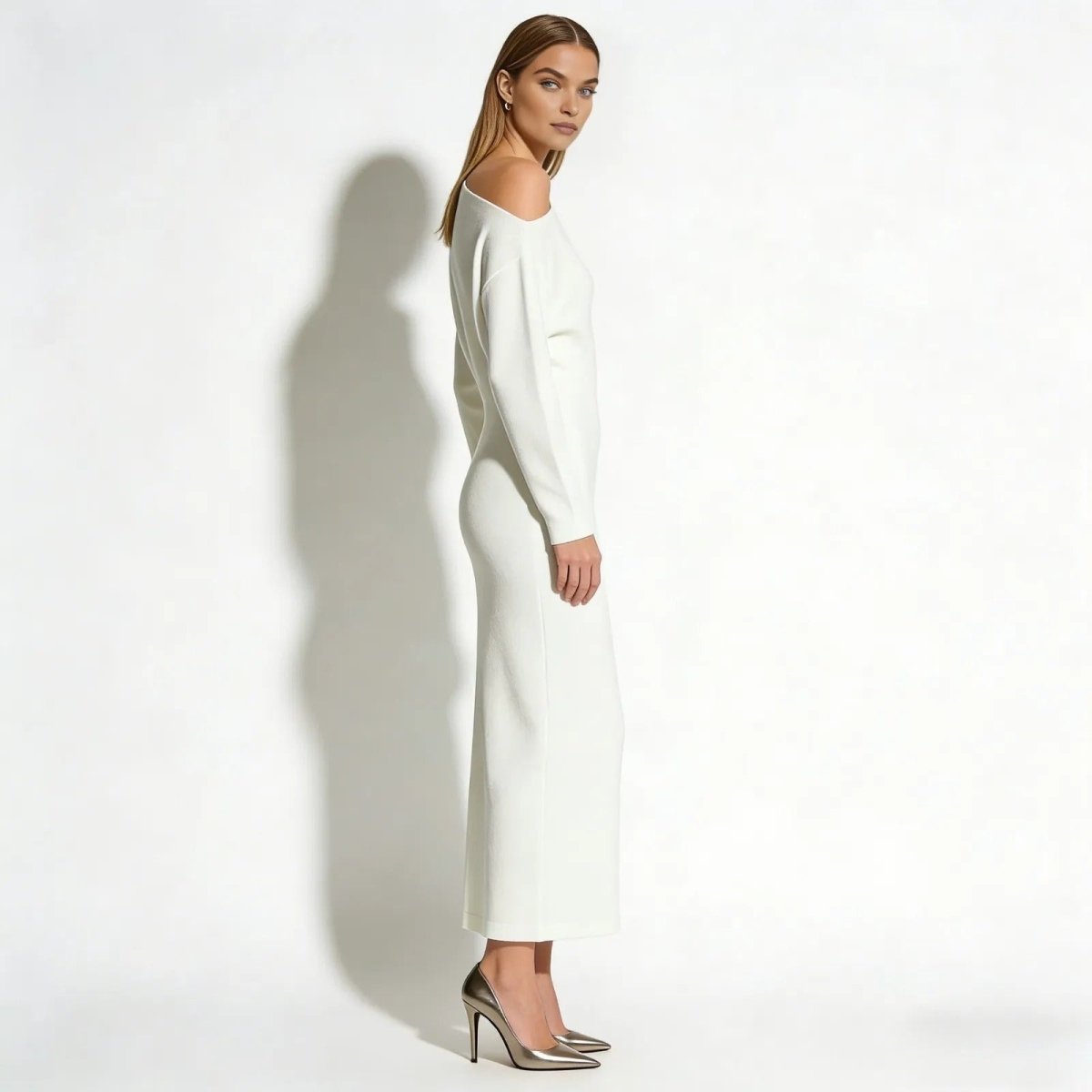 Side profile of a model wearing the Kouvr Fashion Selena asymmetrical long sleeve selena knit dress with metallic heels.