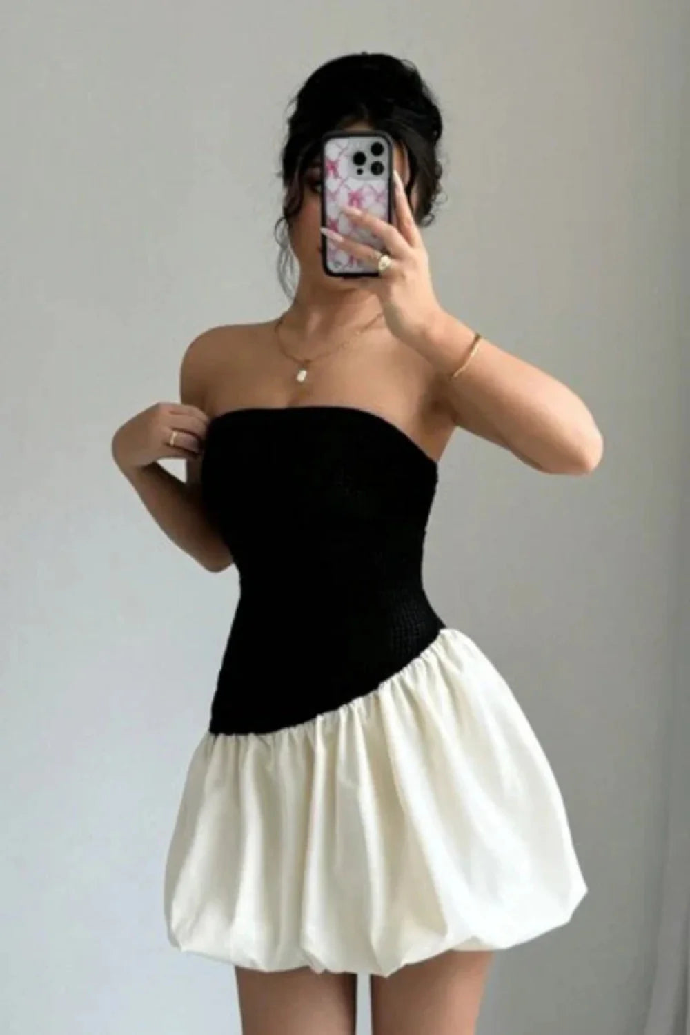 Model wearing Kouvr Fashion strapless black and white bubble hem mini dress against background