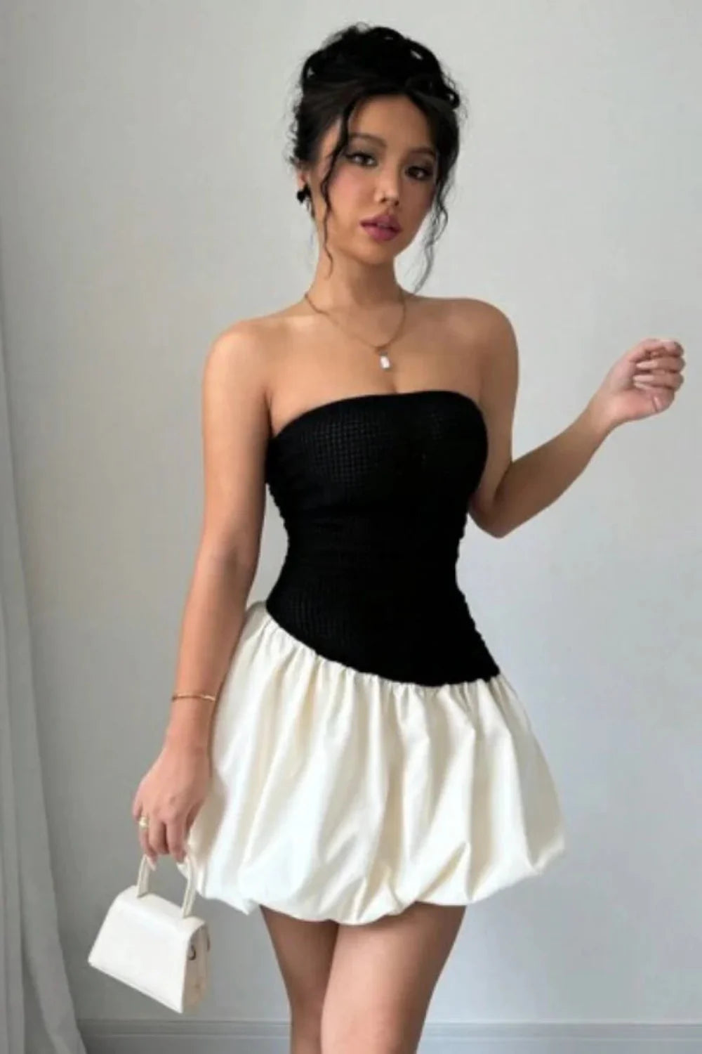 Model wearing Kouvr Fashion strapless black and white bubble hem mini dress against background