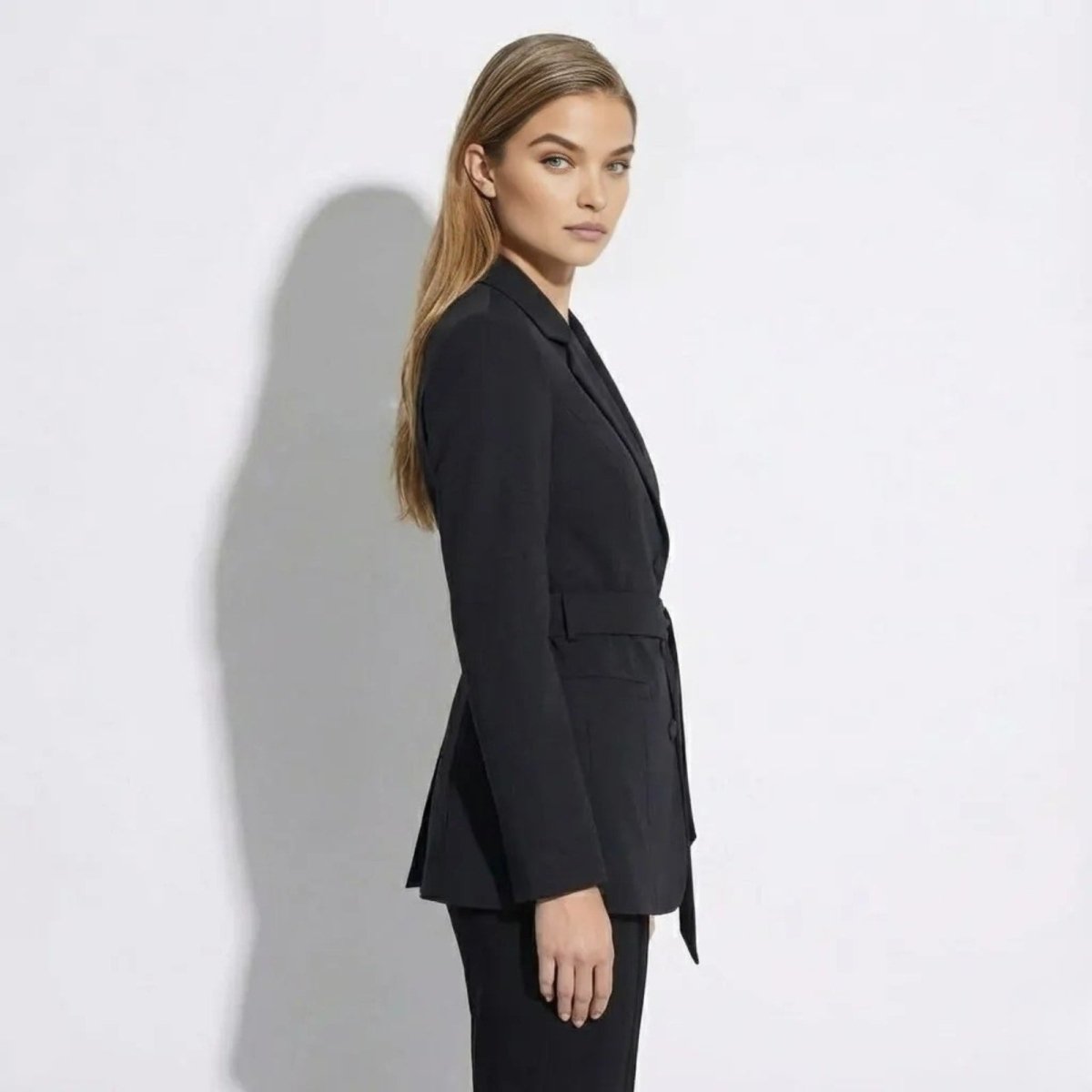 Side profile of a woman wearing the Kouvr Fashion Gemma tailored black blazer to show its structured fit and length.