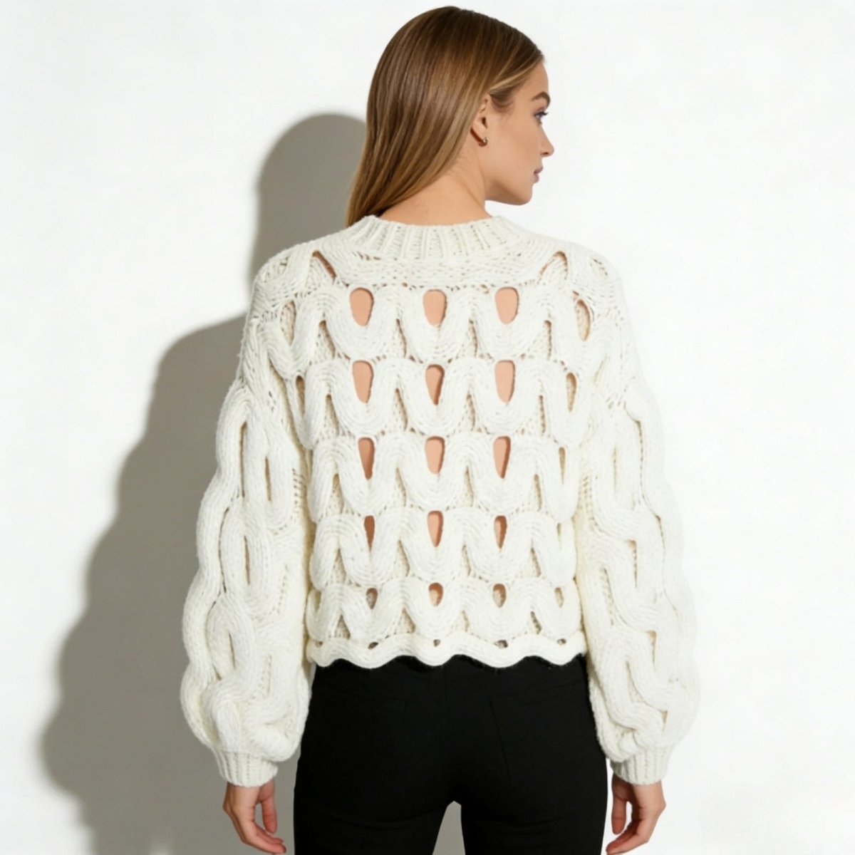 Back view of the Kouvr Fashion white cutout chunky knit sweater, showing the full pattern and cropped, scalloped hem.