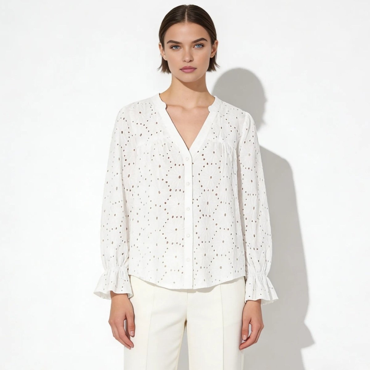 Model wearing the Kouvr Fashion white lydia blouse with a v-neck and long sleeves, paired with cream trousers.