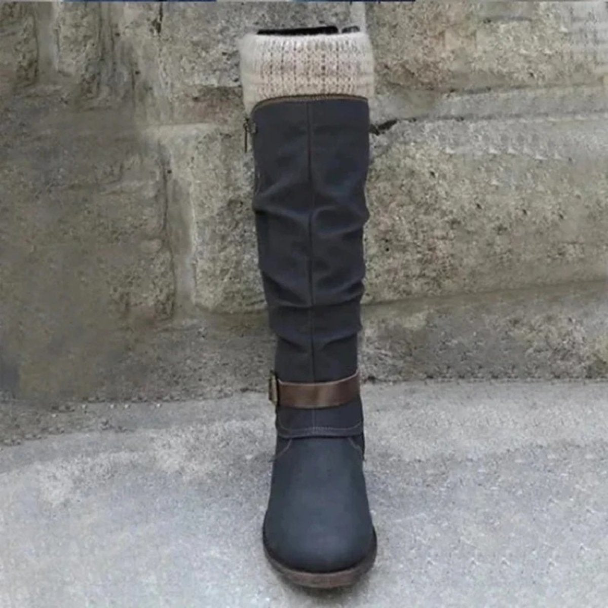 Front view of a single black laura knee-high boot by Kouvr Fashion, showcasing the round toe and ruched shaft against a stone background.