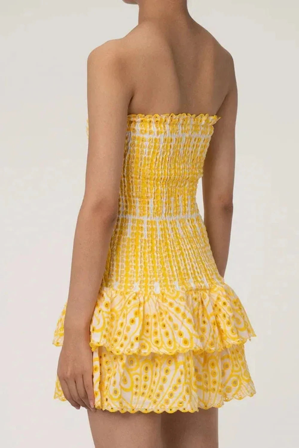 Model wearing Kouvr Fashion strapless yellow eyelet mini dress with tiered ruffle skirt