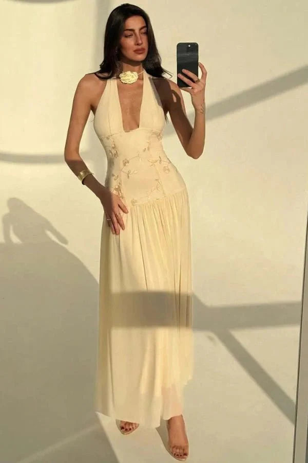 Model wearing the Kouvr Fashion Zoe yellow embroidered halter gown with open back