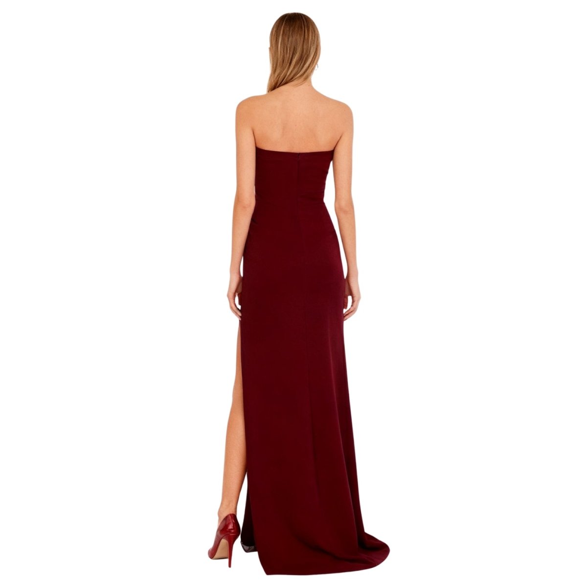 Woman wearing a burgundy kouvr strapless gown with a slit on a white background