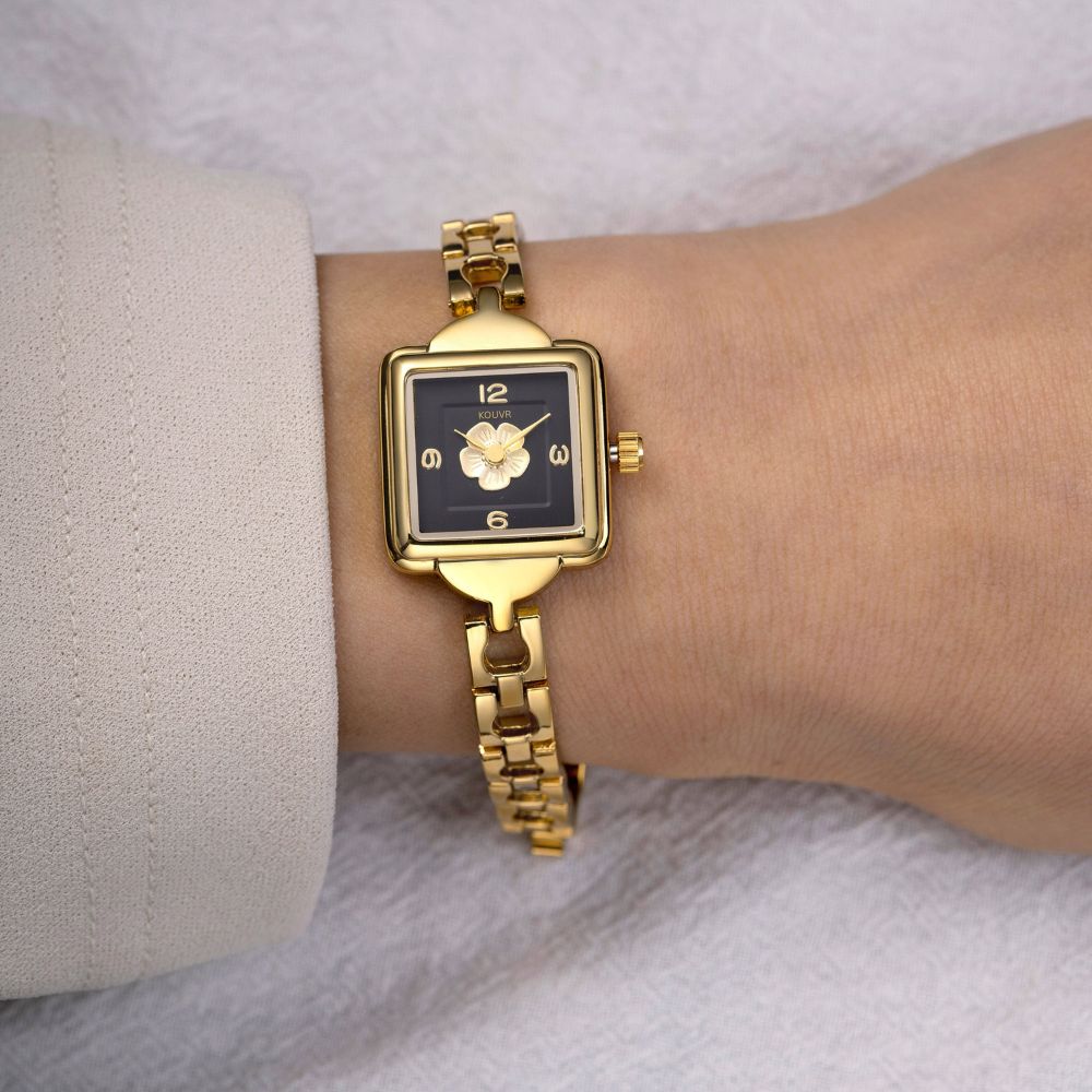 Gold kouvr wristwatch on a wrist with a neutral background