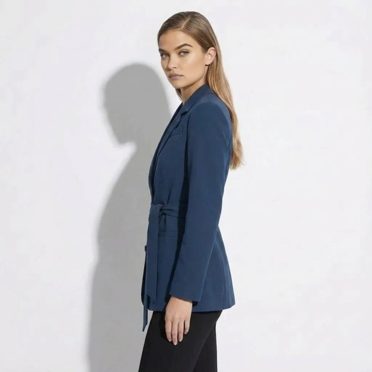 Side profile view of a model in the Kouvr Gemma tie-waist blazer in blue, showcasing its tailored fit and silhouette.