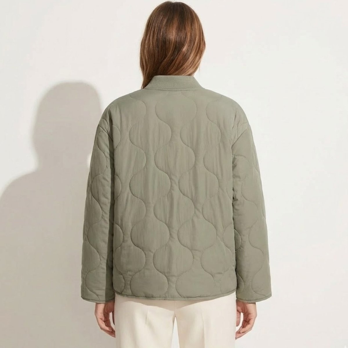 Back view of the Kouvr Harmony sage green quilted jacket on a model, showcasing the full onion quilting pattern and clean silhouette.
