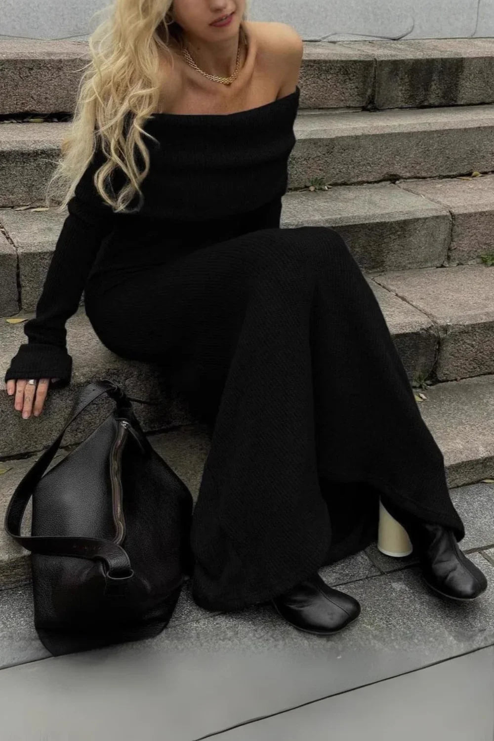 Model from behind wearing Kouvr Ingrid black ribbed knit off the shoulder maxi dress