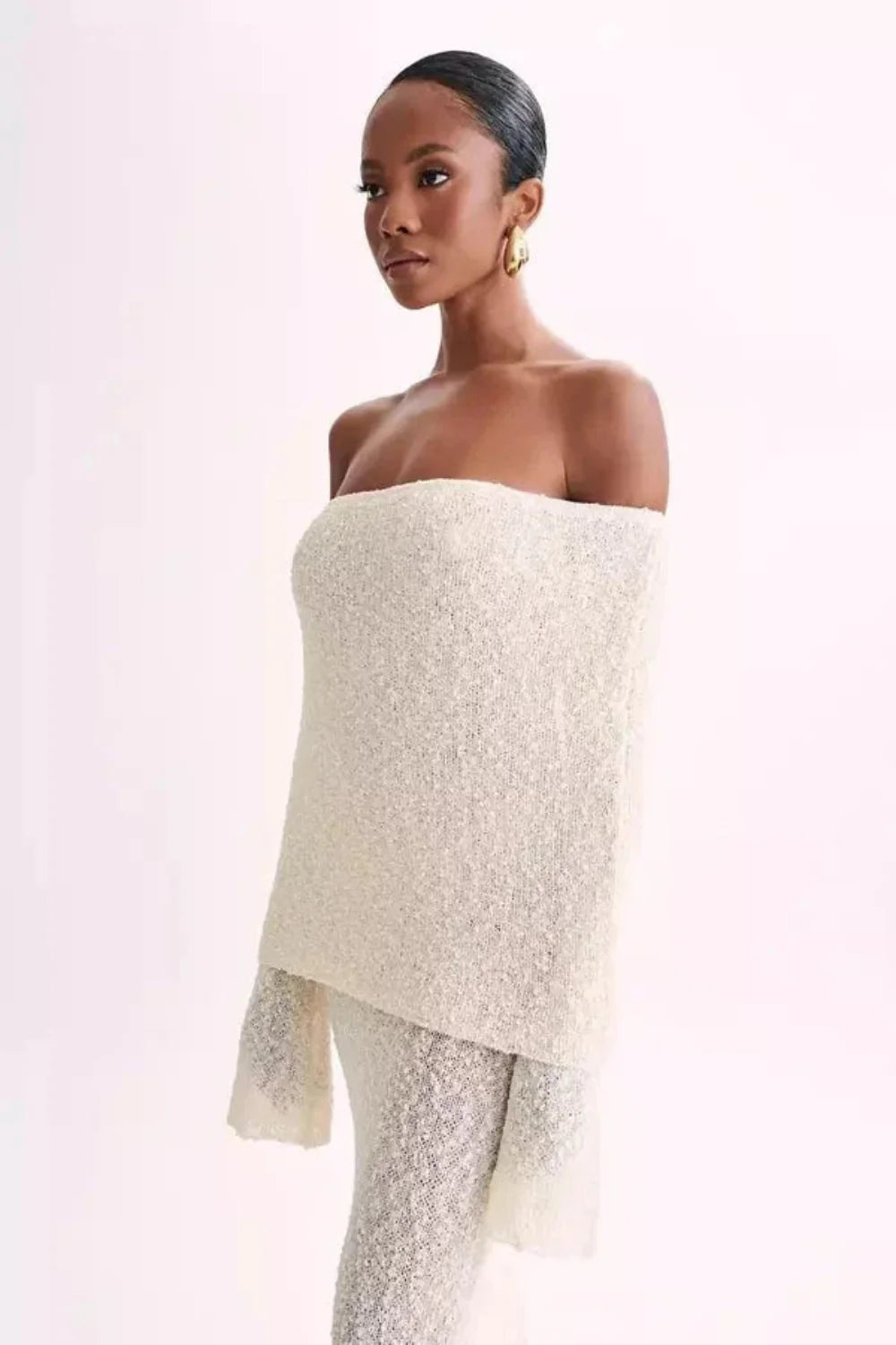 Model wearing Kouvr's ivory off-the-shoulder knit maxi gown, front view