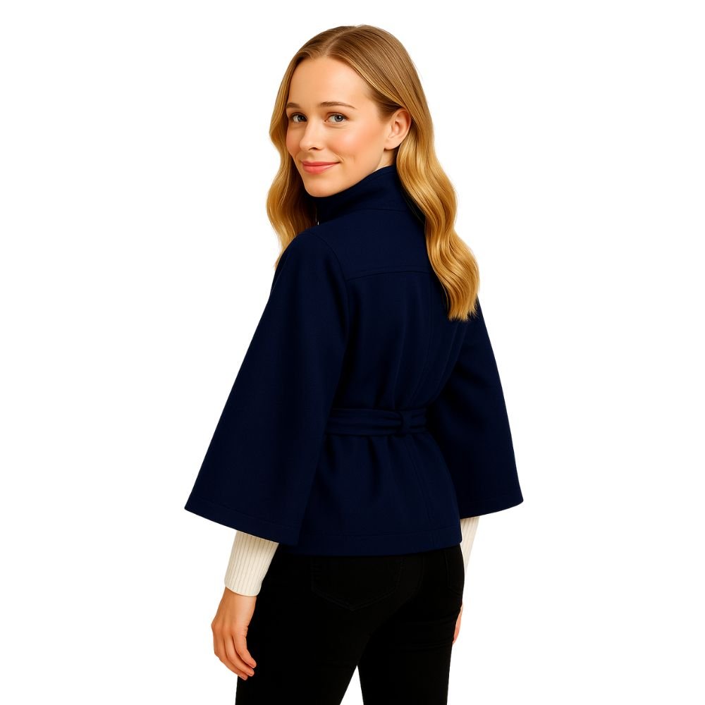 Woman wearing the Kouvr Jaye Cape in navy blue, featuring a high funnel neck, wide sleeves, and a self-tie belt