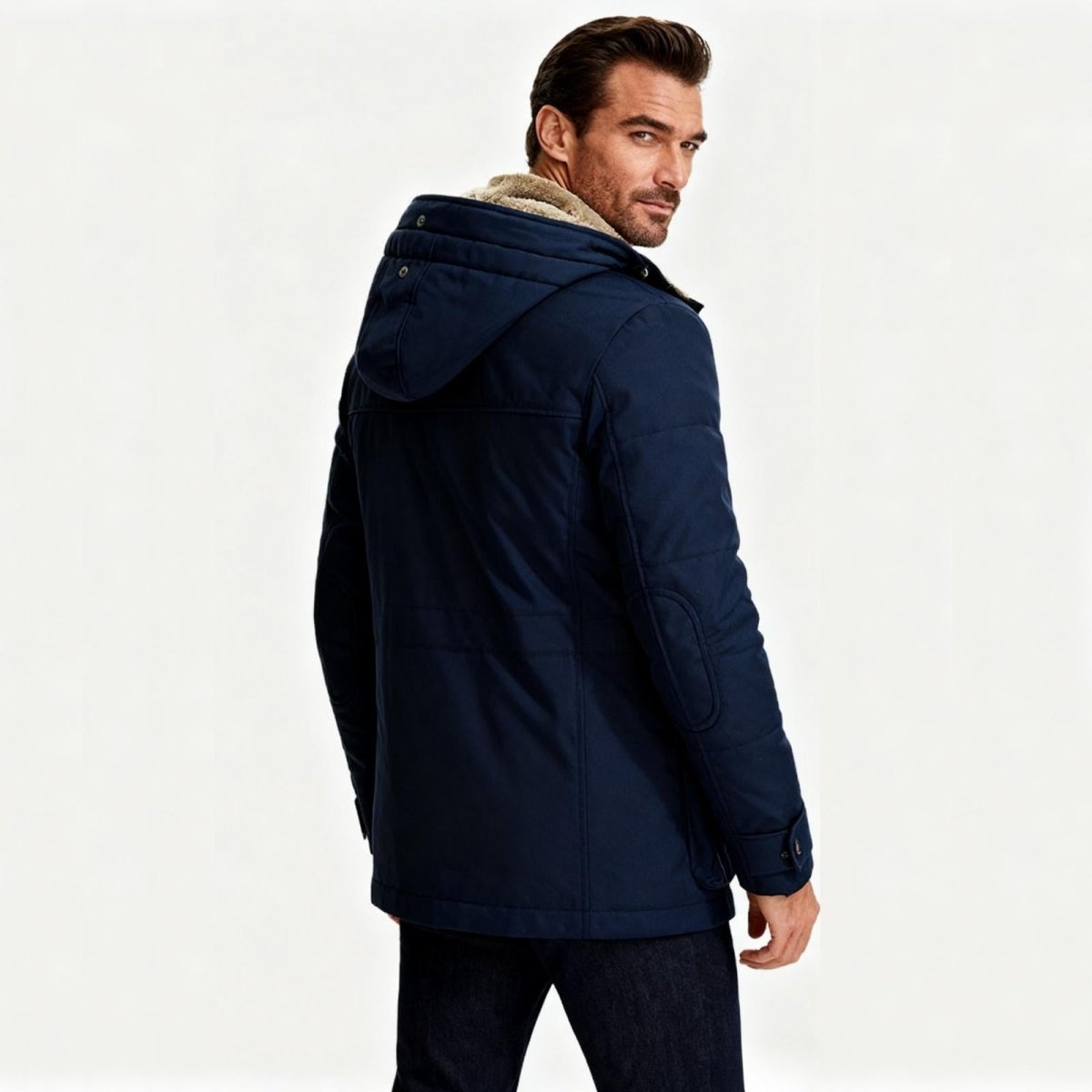 Man wearing a Kouvr navy blue parka with a fur-lined hood on a white background