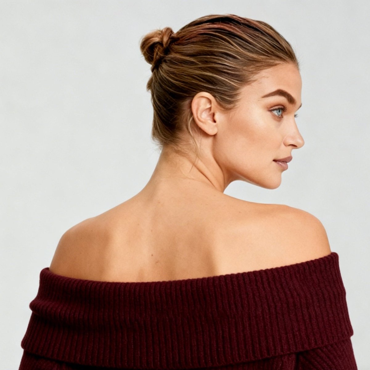Woman wearing a burgundy off-shoulder sweater against a plain background