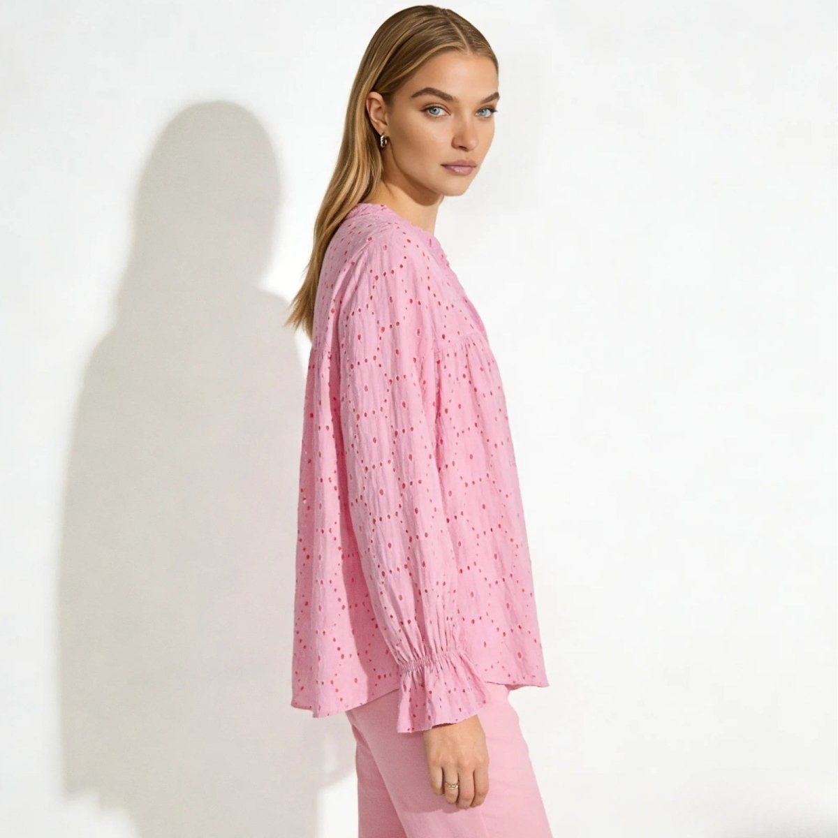 Side profile of a woman wearing the Kouvr pink boho eyelet blouse, highlighting the voluminous bishop sleeves and relaxed fit.