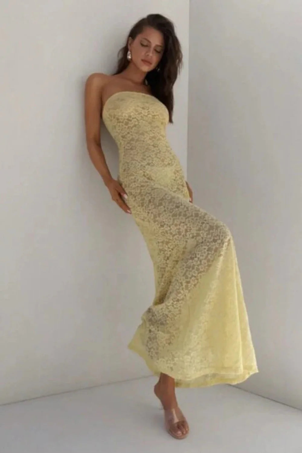 Model wearing the Kouvr Mariposa strapless lace floor-length dress in Buttercup Yellow against a white wall