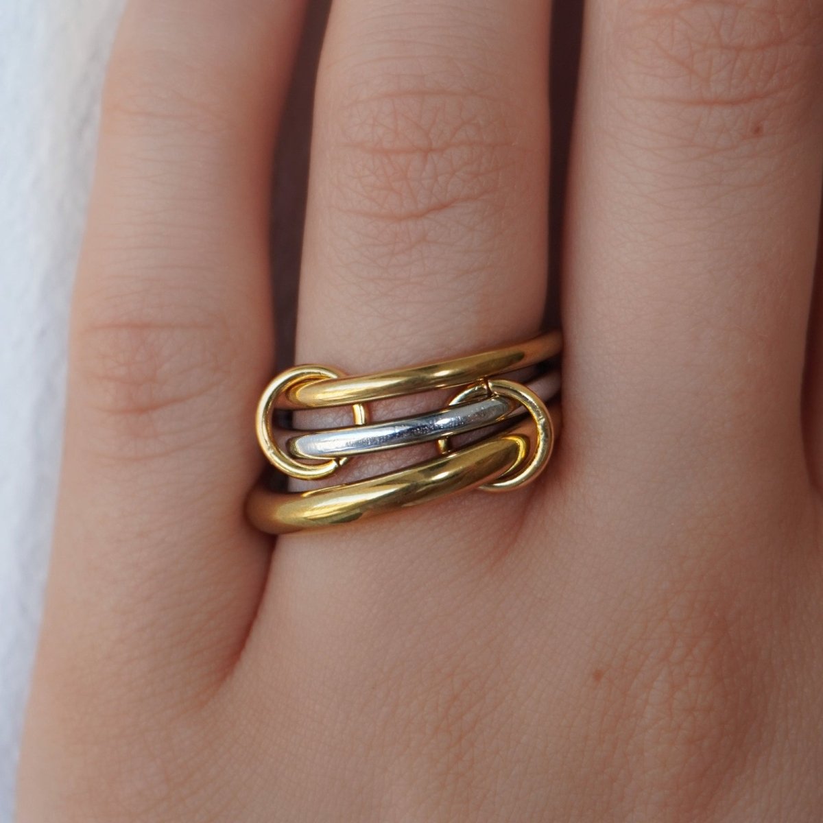 A woman wearing the Kouvr Mavis three-band interlocking rolling ring in 18k gold and sterling silver.