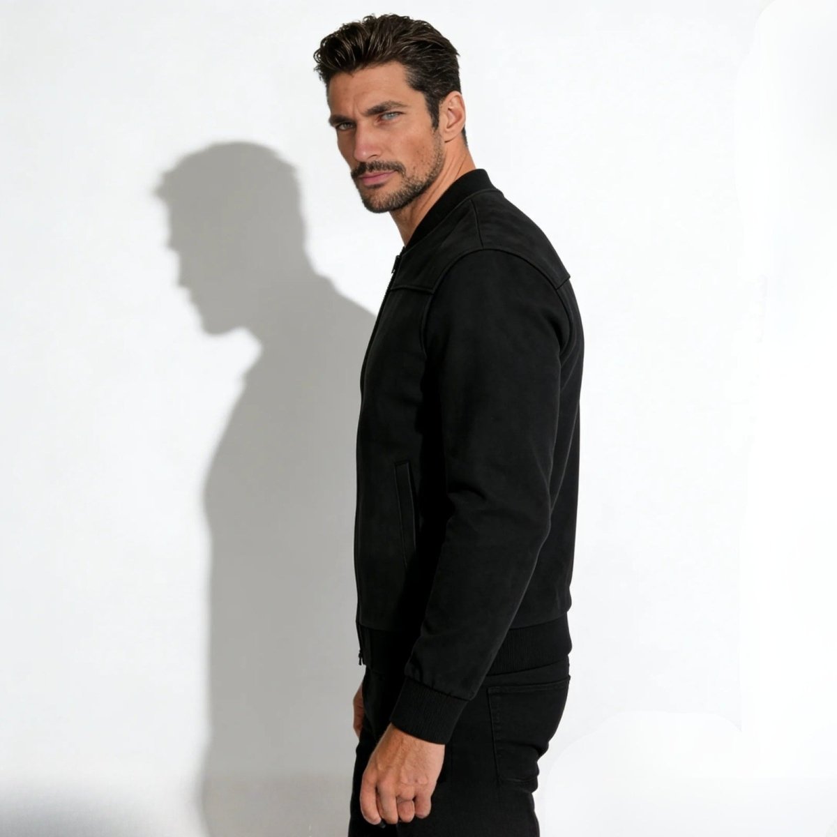Side profile view of a model wearing the Kouvr slim fit black suede designer jacket, showing its silhouette.