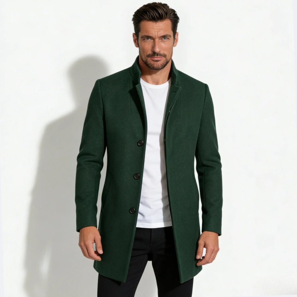 Model wearing a dark forest green men's wool stand collar overcoat from Kouvr Fashion, styled with a white t-shirt and black trousers.