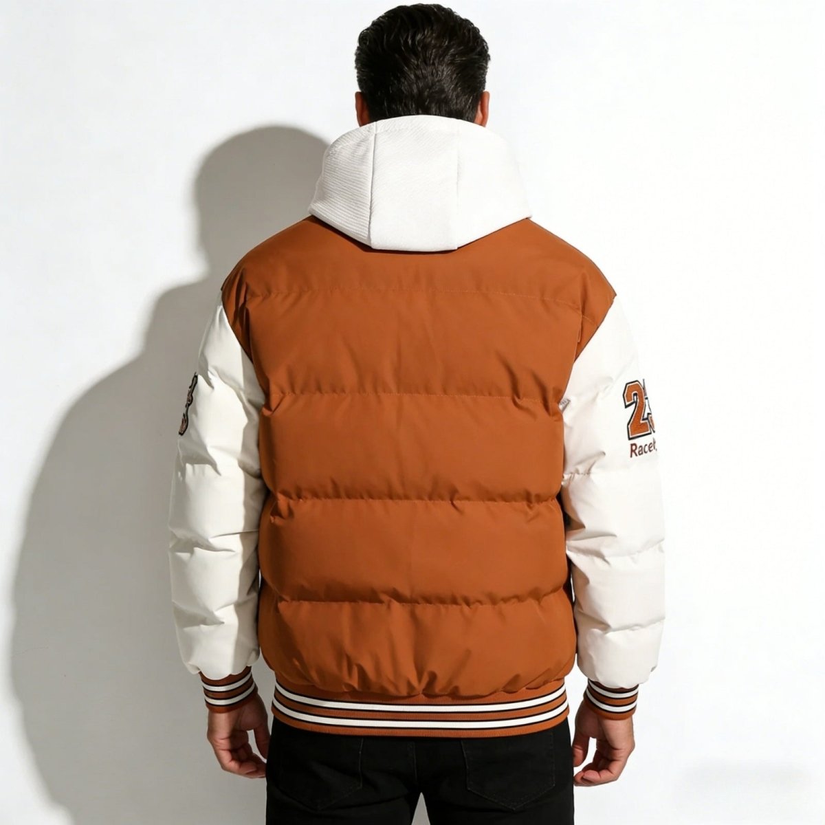 Back view of the Kouvr men's varsity puffer jacket, showcasing the horizontal quilting on the brown body and the white hood.