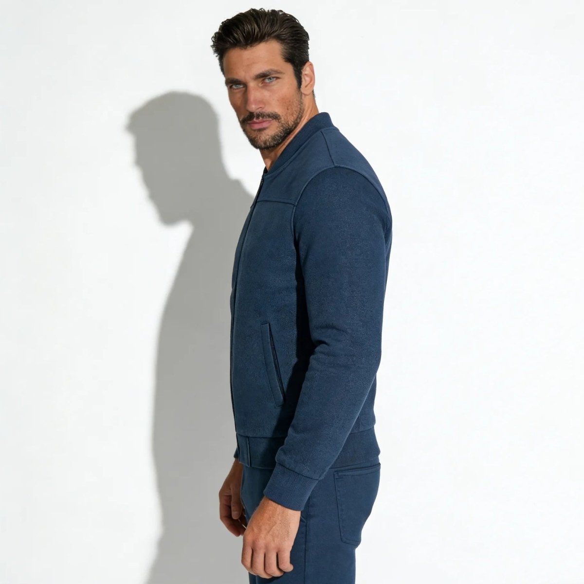 Side profile of a man wearing the slate blue Kouvr Michael suede bomber jacket, highlighting the sleeve construction and silhouette.