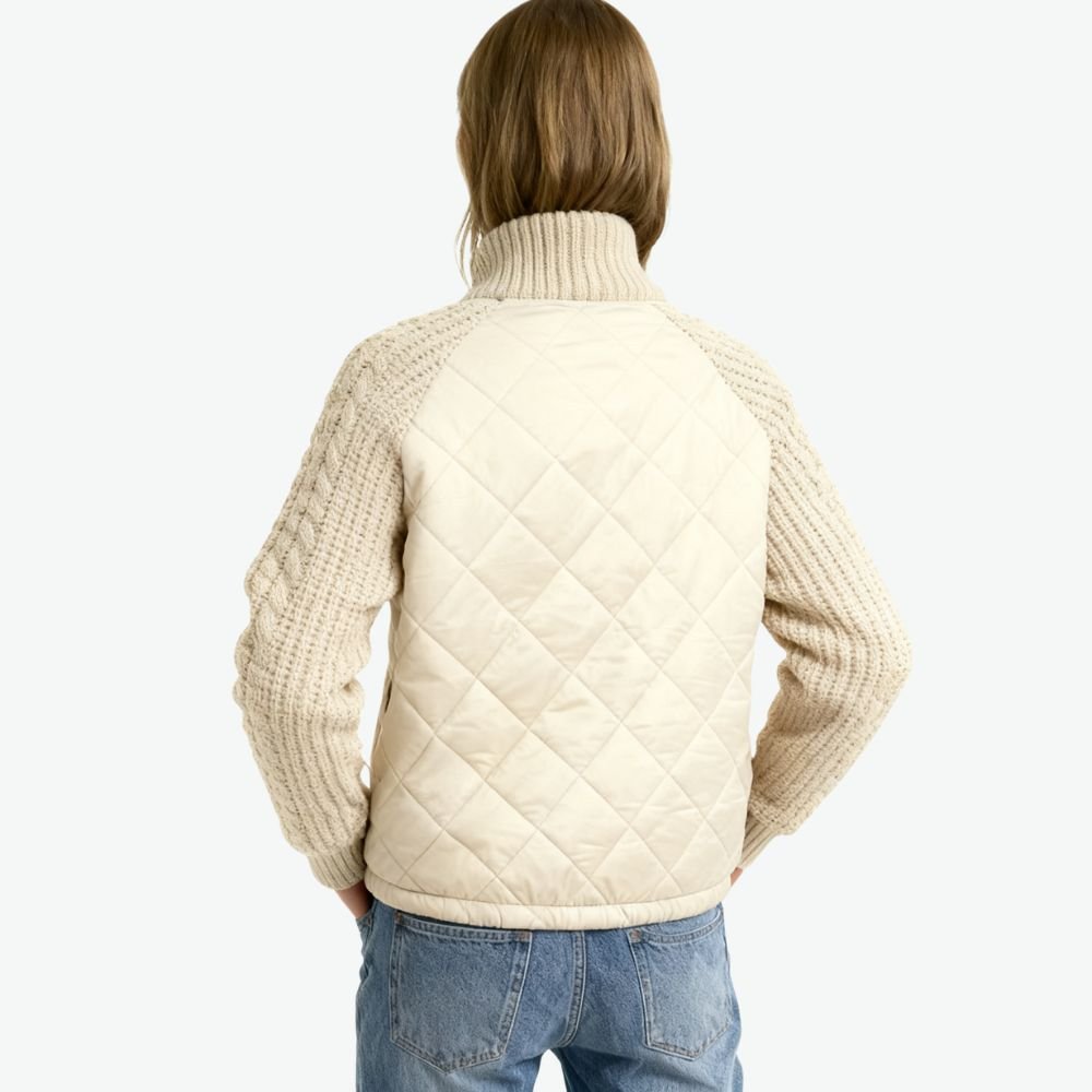 Woman wearing the Kouvr Mika khaki quilted jacket with cable knit sleeves, styled with jeans