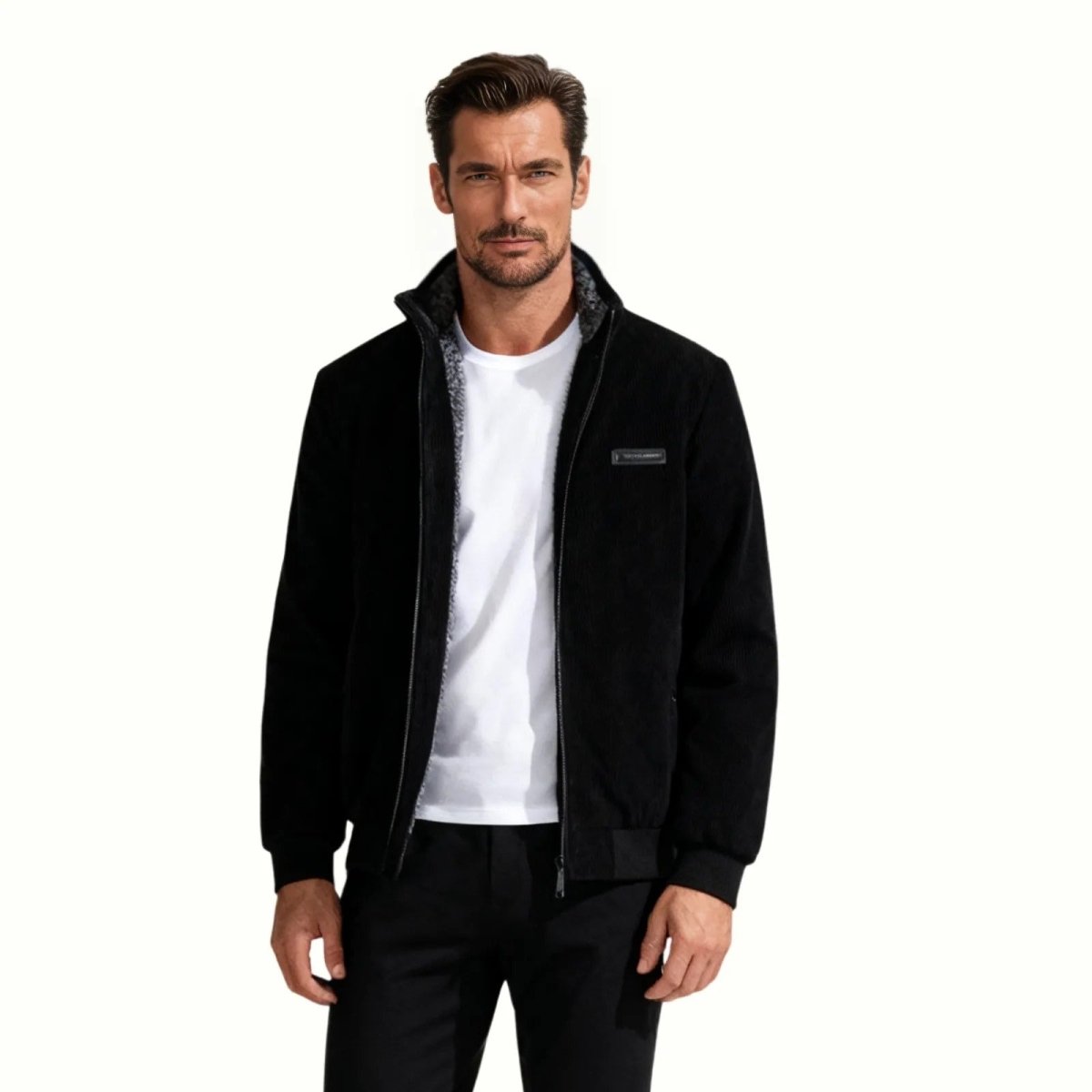 Man wearing the Kouvr Nick black corduroy jacket with a grey shearling lined collar, shown from the front over a white t-shirt.
