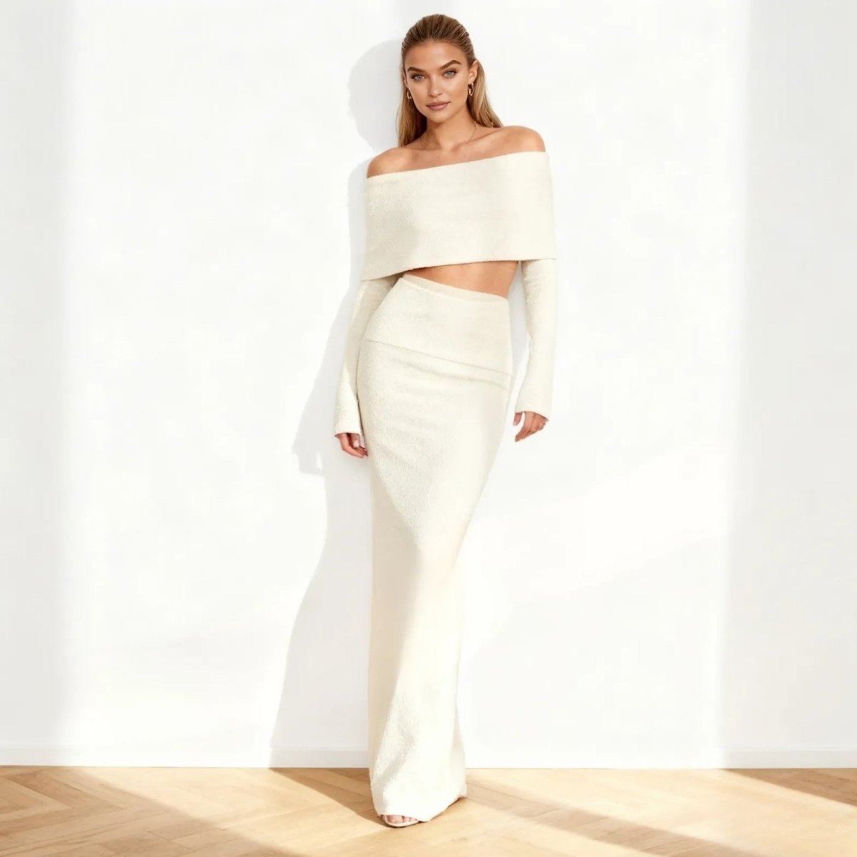 Woman wearing a white Kouvr off-shoulder top and skirt set on a plain background