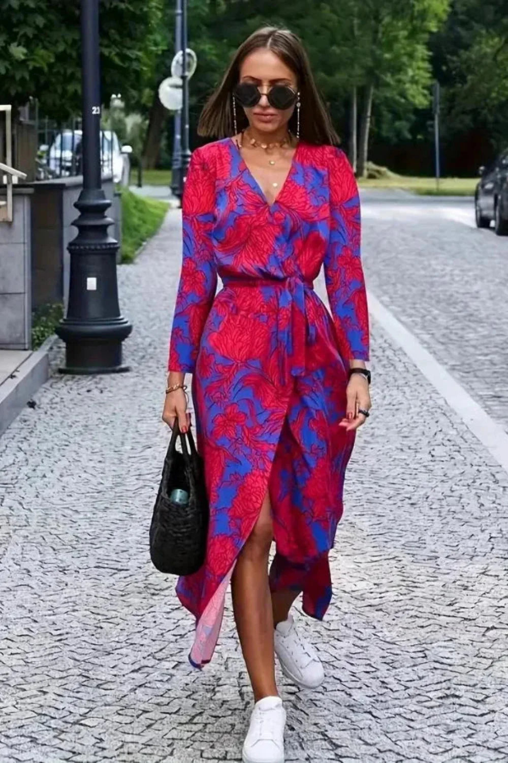 Model wearing the Aleia red and blue floral silk wrap dress with white sneakers and a black bag.