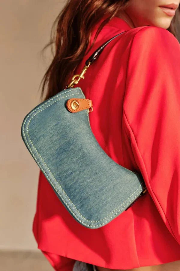 Model wearing the Kouvr Romy denim baguette bag with a red blazer to show scale.