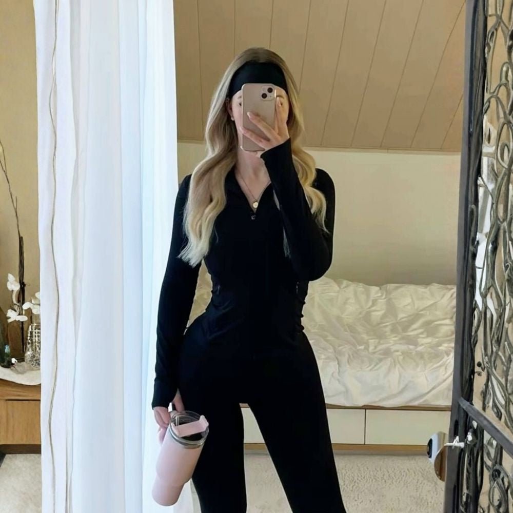 Woman wearing the black Kouvr Sculpting Athletic Jacket in a modern fitness studio.