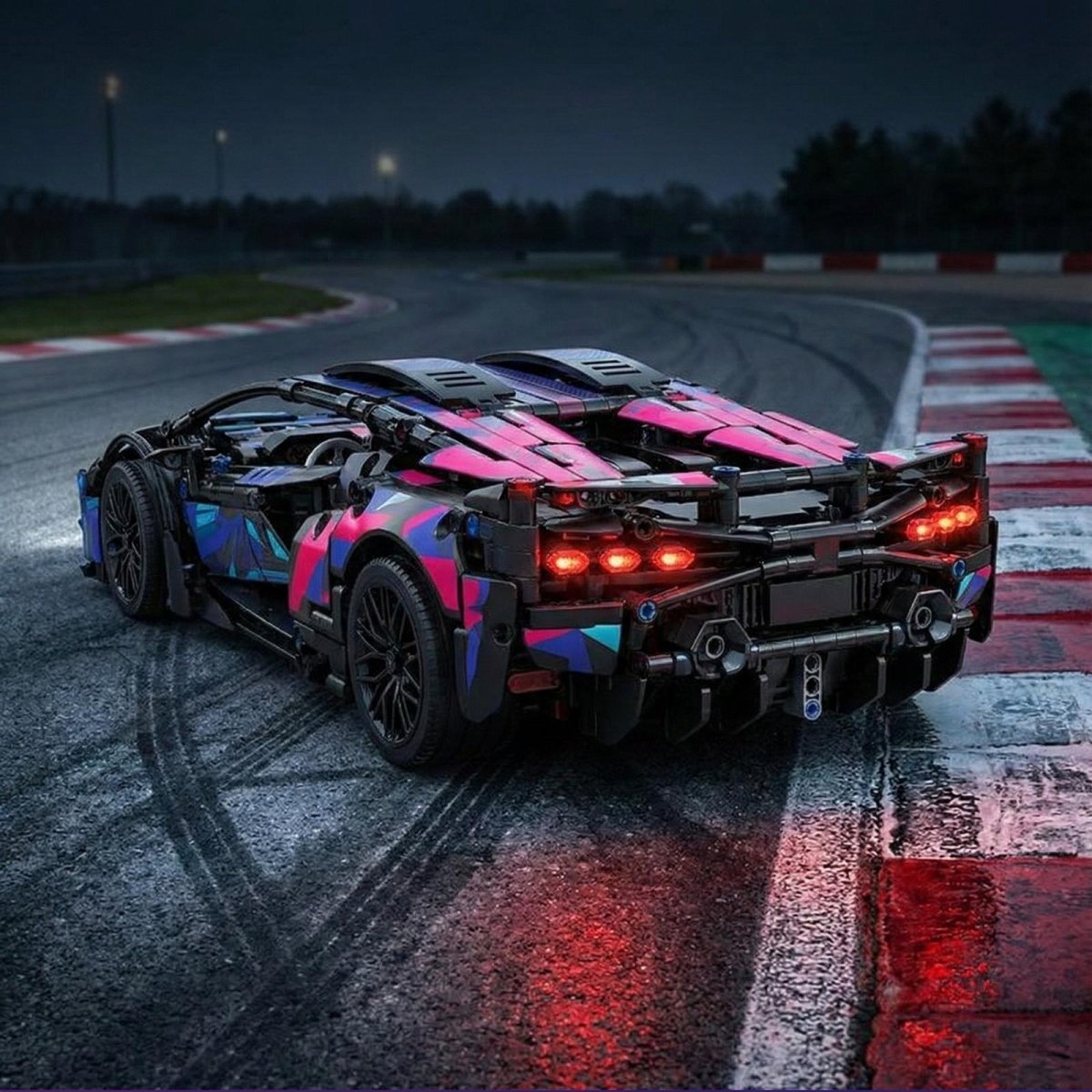 Rear view of the Kouvr Spectre Racer building kit on a racetrack curb, showcasing the illuminated red LED taillights and detailed exhaust system.