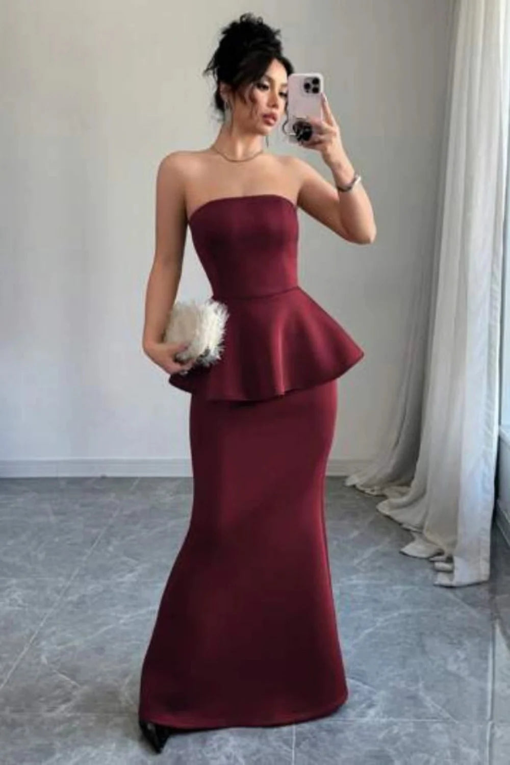 Model wearing Kouvr's burgundy strapless peplum mermaid gown for a formal event