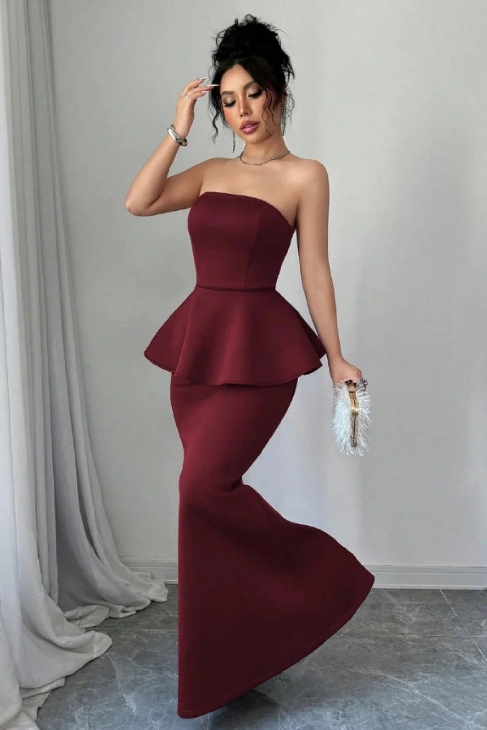 Model wearing Kouvr's burgundy strapless peplum mermaid gown for a formal event