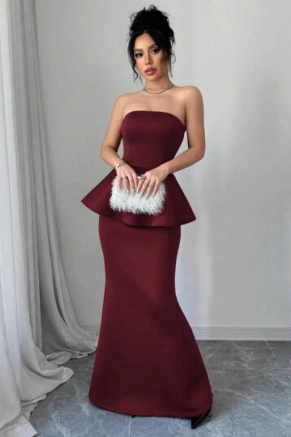 Model wearing Kouvr's burgundy strapless peplum mermaid gown for a formal event