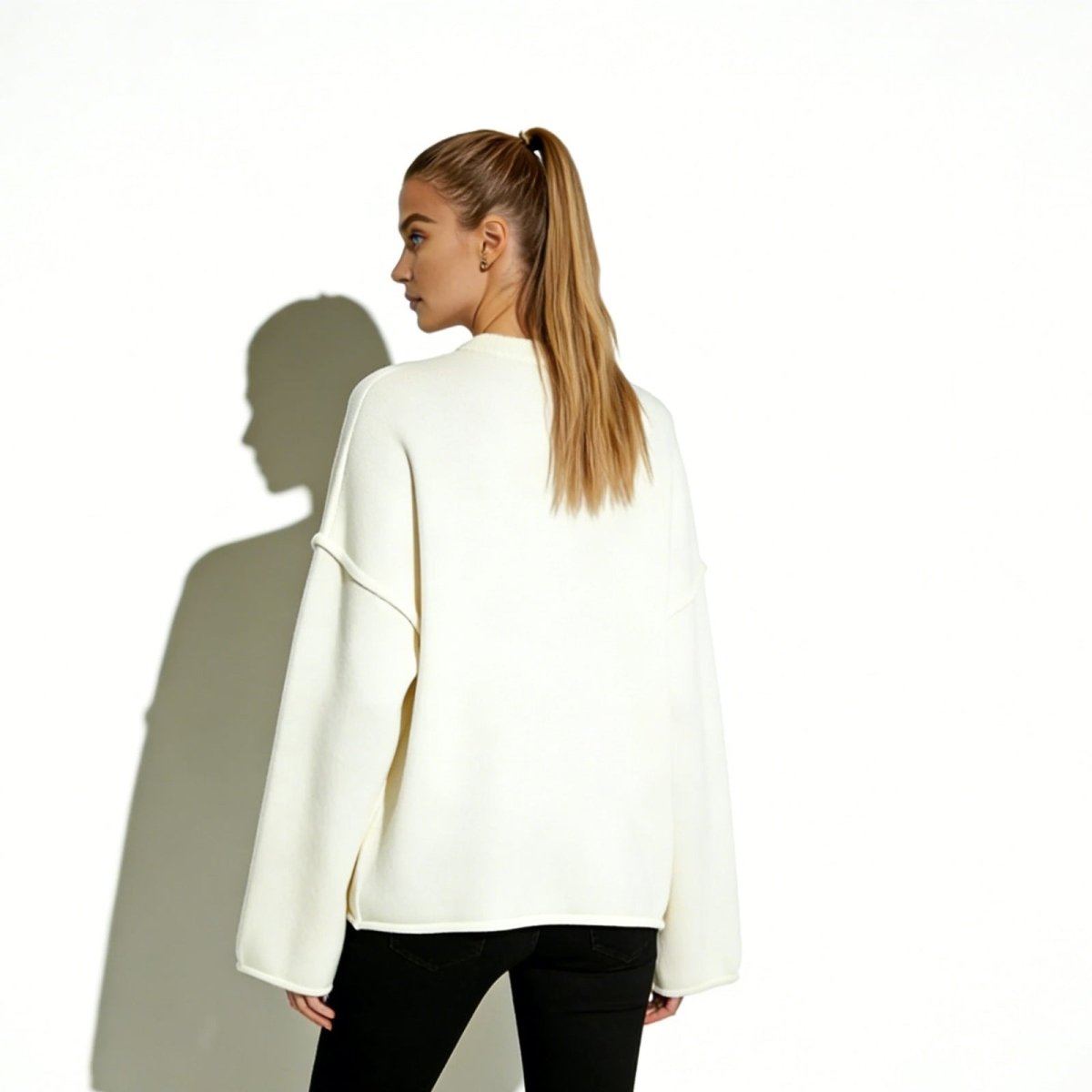 Back view of the Kouvr minimalist ivory knit pullover on a model, highlighting the clean architectural lines and relaxed oversized fit.