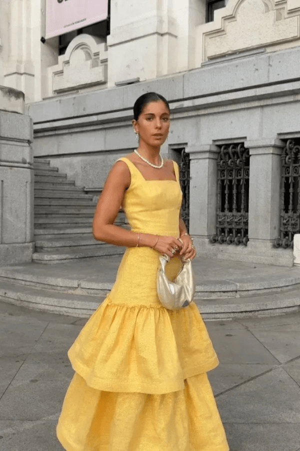 Model wearing the Kouvr Valeria canary yellow tiered ruffle maxi dress at an outdoor event