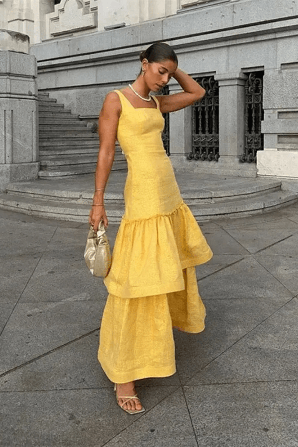 Model wearing the Kouvr Valeria canary yellow tiered ruffle maxi dress at an outdoor event