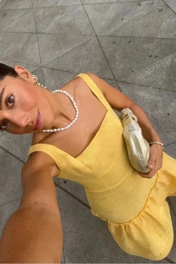 Model wearing the Kouvr Valeria canary yellow tiered ruffle maxi dress at an outdoor event