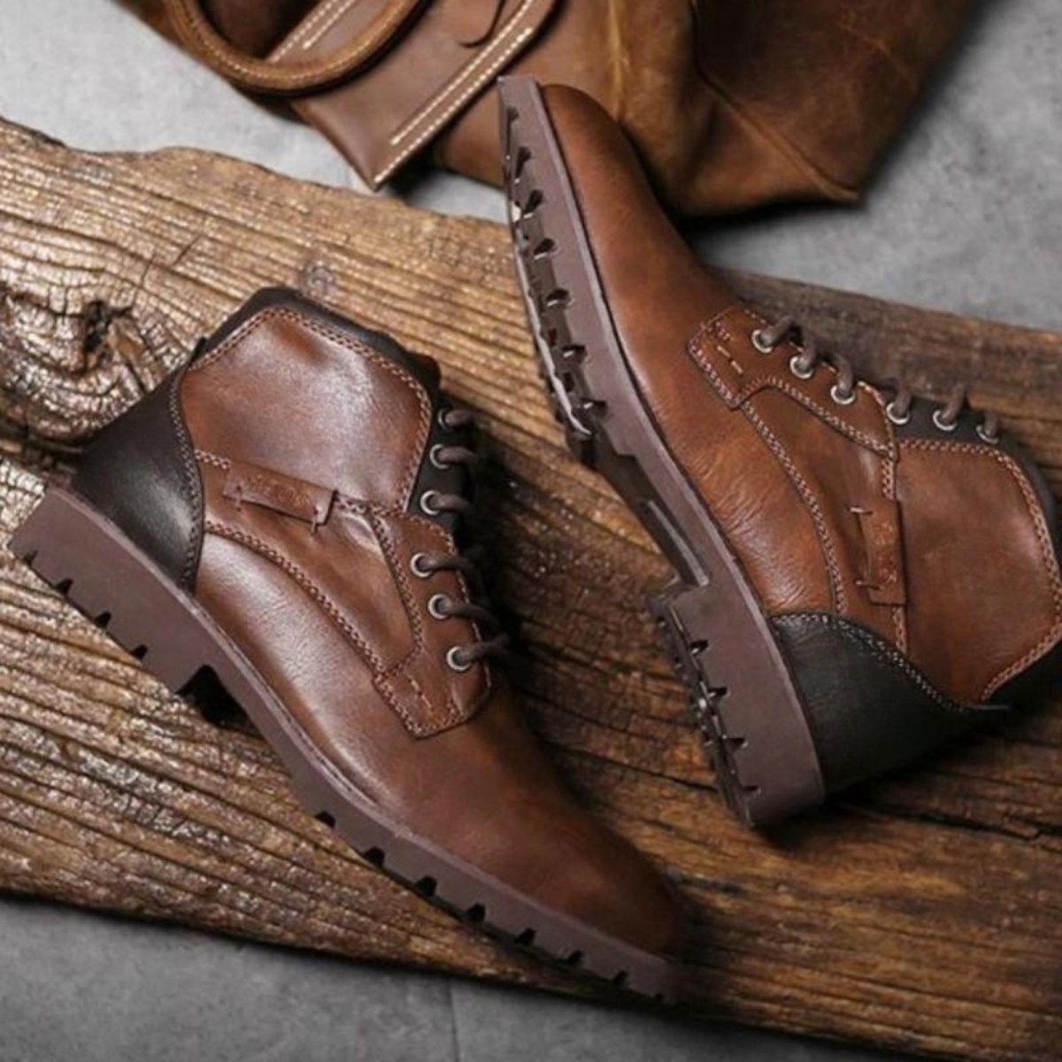 Brown leather boots on a wooden surface with a gray background