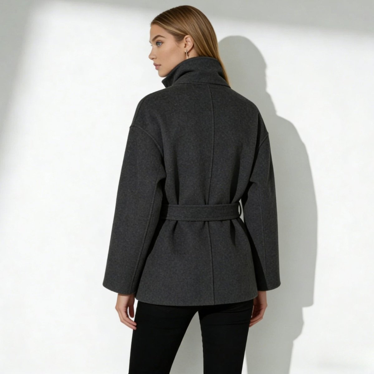 Back view of the Kouvr Verna belted wool coat in dark gray, highlighting the clean lines and belt detail.