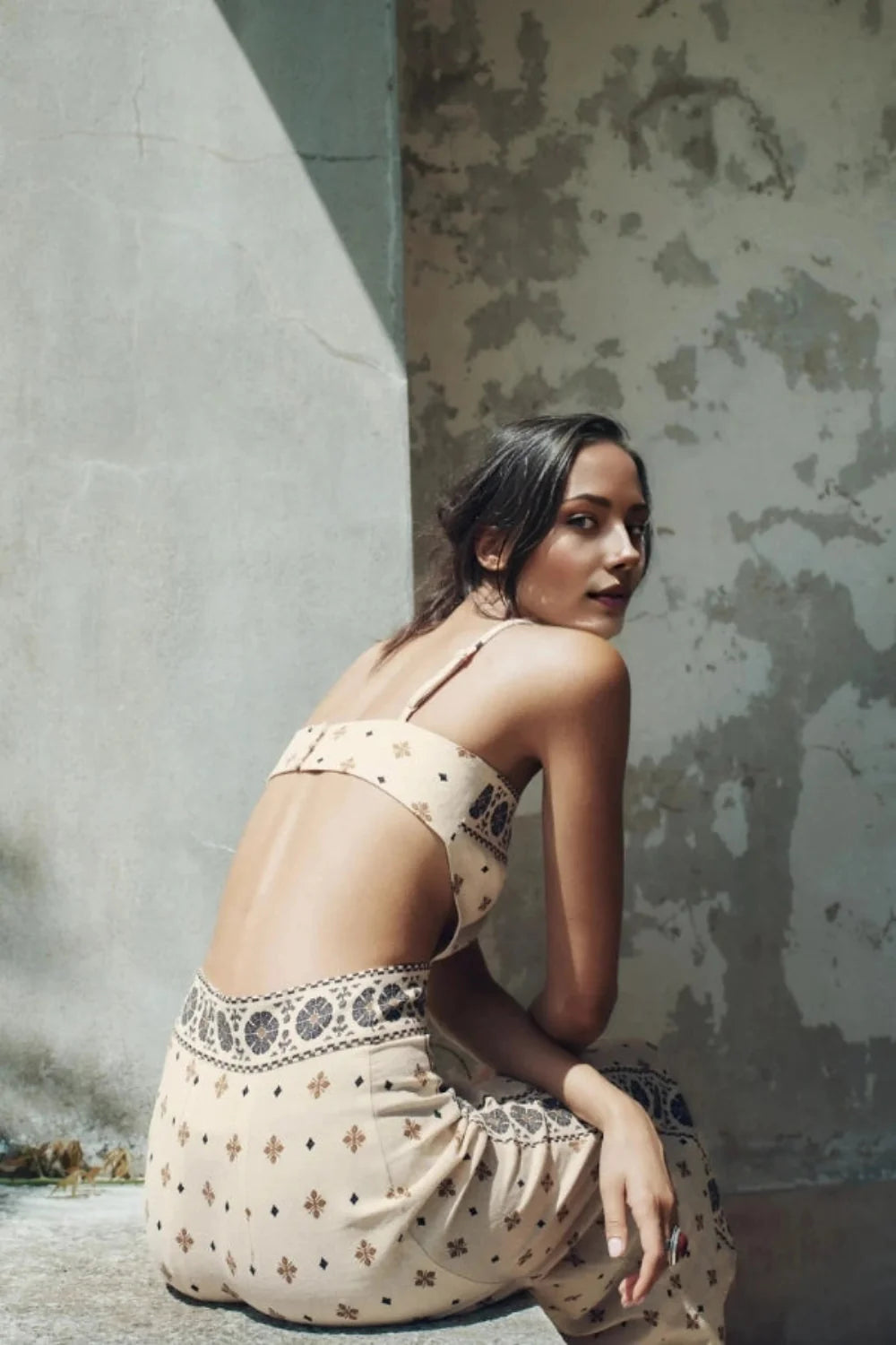 Model wearing Kouvr Vernice embroidered linen cutout midi dress sitting outdoors