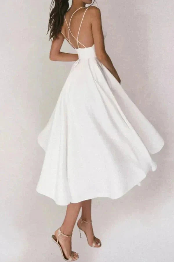 Model from behind wearing The Alazne white satin midi dress showing the criss-cross open back straps