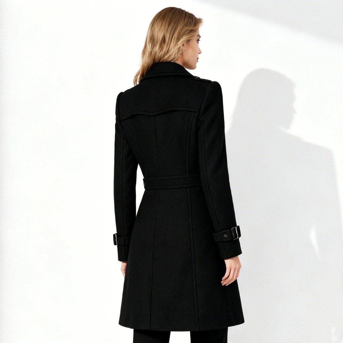 Woman wearing a black Kouvr coat against a white background