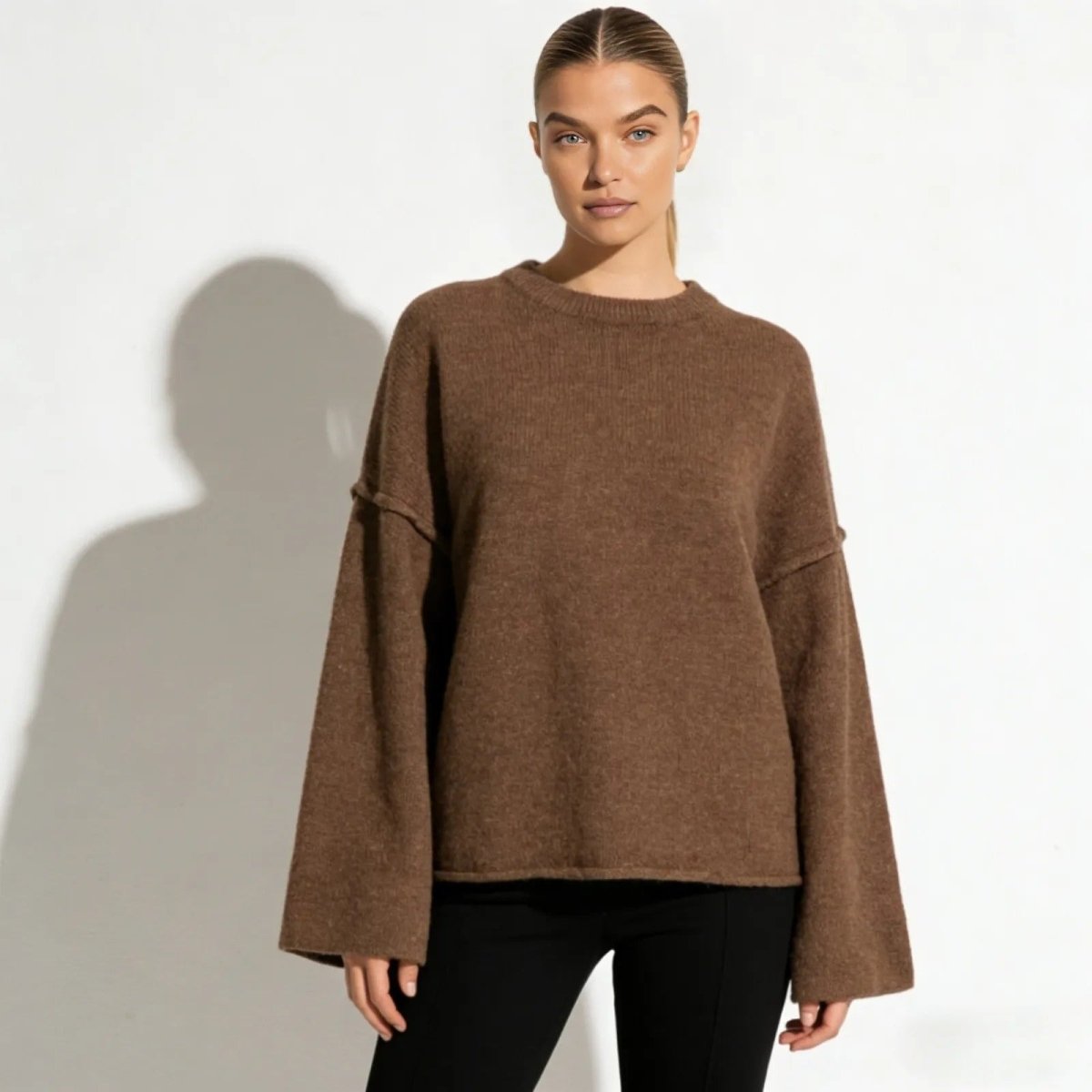 Model wearing the Kouvr Krystal oversized bell sleeve sweater in a rich brown, showing the relaxed fit and crewneck from the front.