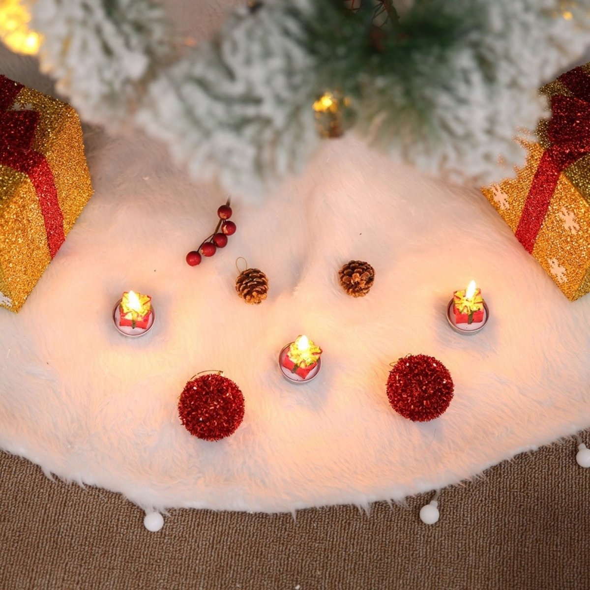 Top-down view of a plush snowy white Christmas tree skirt decorated with flameless candles, pinecones, and red ornaments under a tree.