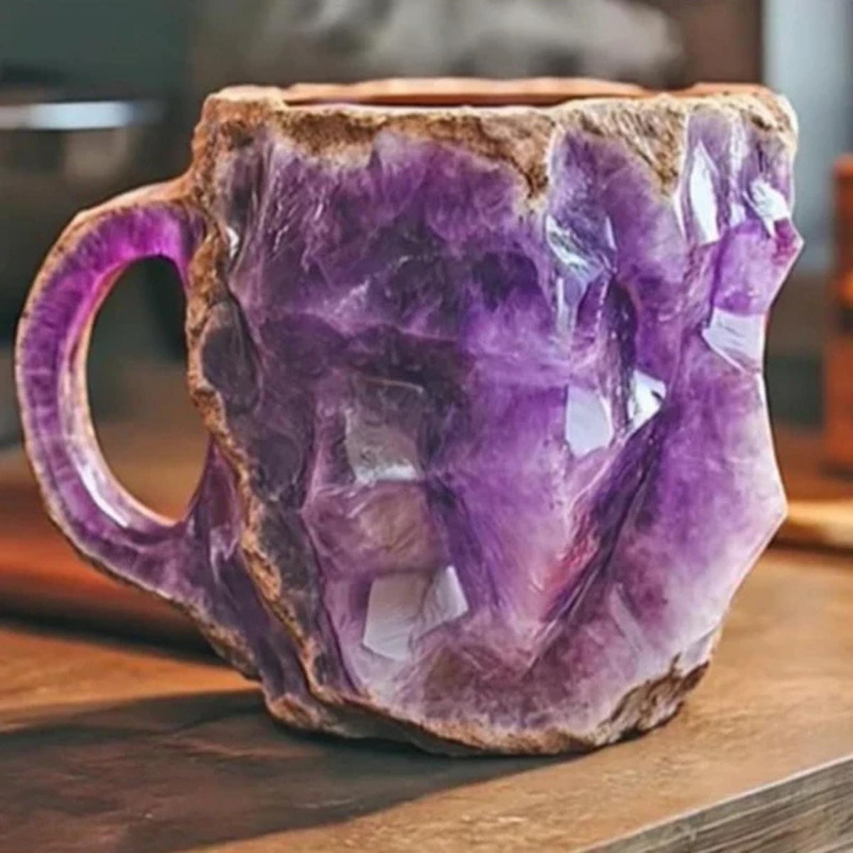 A handcrafted raw amethyst crystal mug by Kouvr sitting on a wooden surface, showing its deep purple facets and rugged texture.