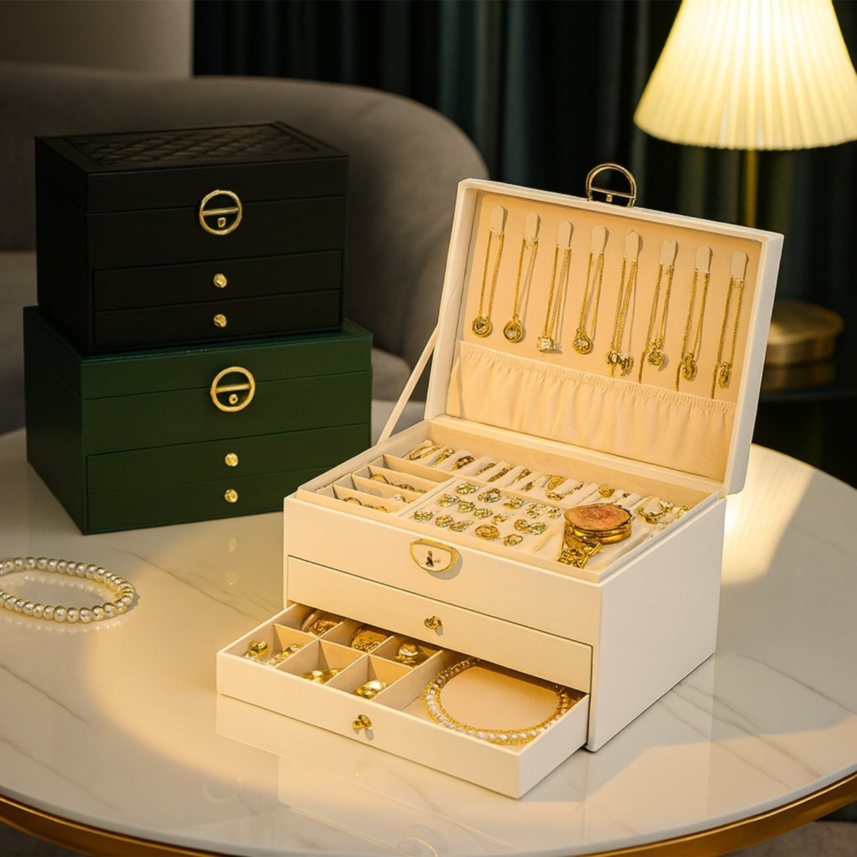 White open jewelry organizer sitting in front of stacked black and green storage cases, showing color variety and gold hardware.